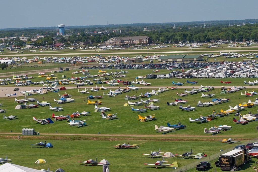 Aerial view of hundreds of light aircraft and campers' tents parked in rows on the grass at EAA AirVenture Oshkosh