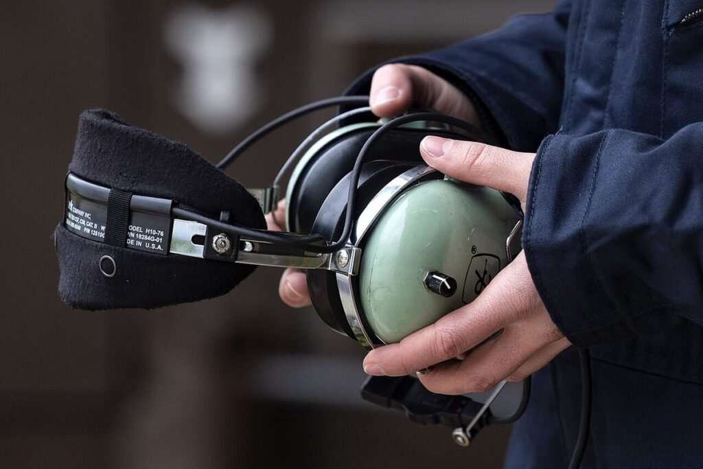 Close-up of hands holding a green David Clark aviation headset with a padded headband