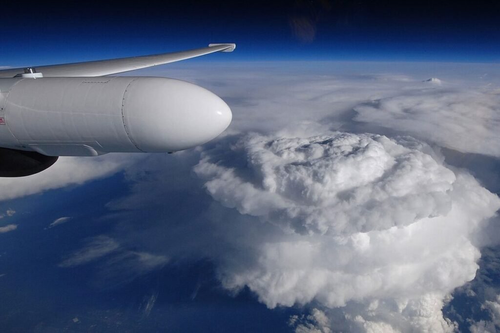Towering thunderstorm cloud rising above a storm system, seen from a NASA ER-2 high-altitude aircraft with its wing pod in view