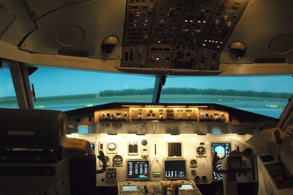 Airliner flight deck of a Fokker 100 simulator seen from behind the pilot seats with a runway on the visual screen