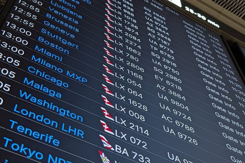 Airport departure board listing flights to Boston, Miami, Chicago, Washington, London and Tokyo, seen at an angle