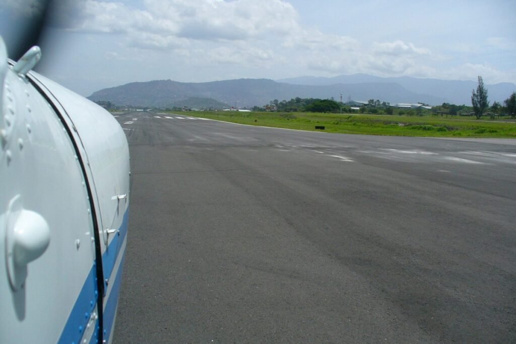 View from a small airplane lined up on a runway with green hills and mountains ahead