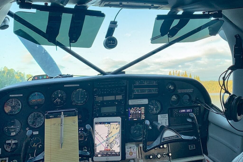 Instrument panel of a Cessna 206 seaplane with an iPad running ForeFlight and a notepad clipped below the gauges