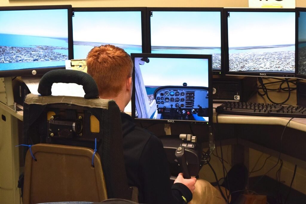 Student seen from behind flying a desktop flight simulator with a joystick and a wall of monitors